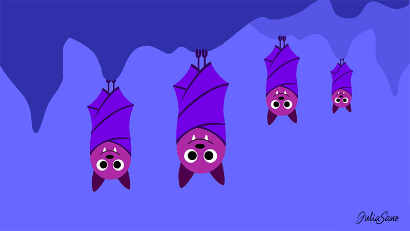 Happy bats hanging from some rocks inside a cave.